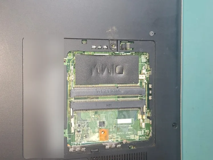 Notebook Dell por baixo com a tampa da memória aberta, mostrando os slots