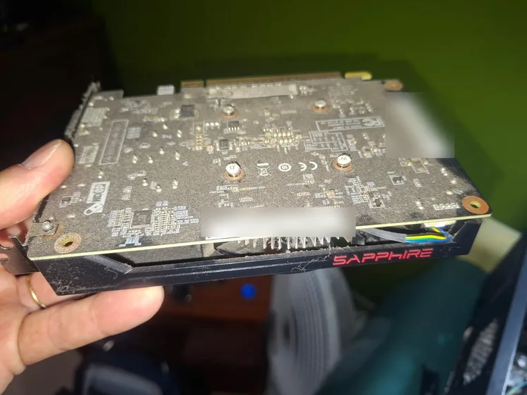Placa de vídeo Sapphire com poeira no dissipador, segurada na mão