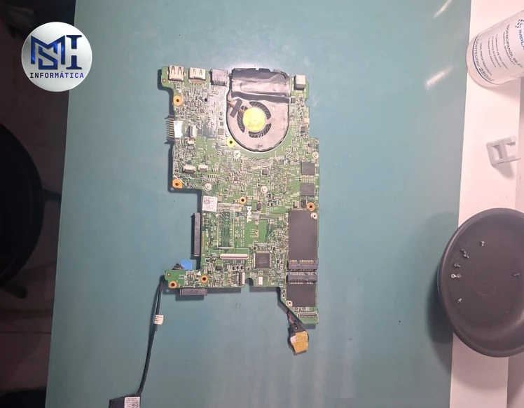 Placa-mãe de notebook Dell Inspiron fora do gabinete, com o cooler e a saída de ar ainda presos