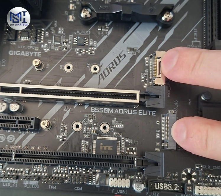 Dedos marcando os encaixes de SSD M.2 numa placa-mãe Gigabyte B550M AORUS ELITE, para saber qual SSD escolher