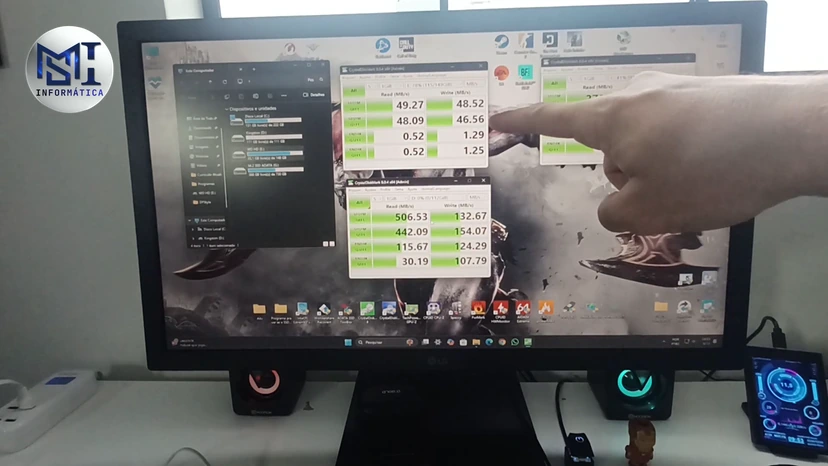CrystalDiskMark no monitor com o teste de dois discos, um perto de 50 MB/s e outro perto de 500 MB/s, com o dedo do técnico apontando, no vídeo do canal