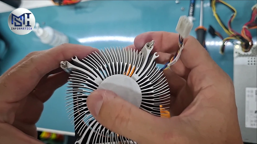 Mãos do técnico segurando o dissipador do cooler Intel de um Dell Vostro durante a limpeza, no vídeo do canal