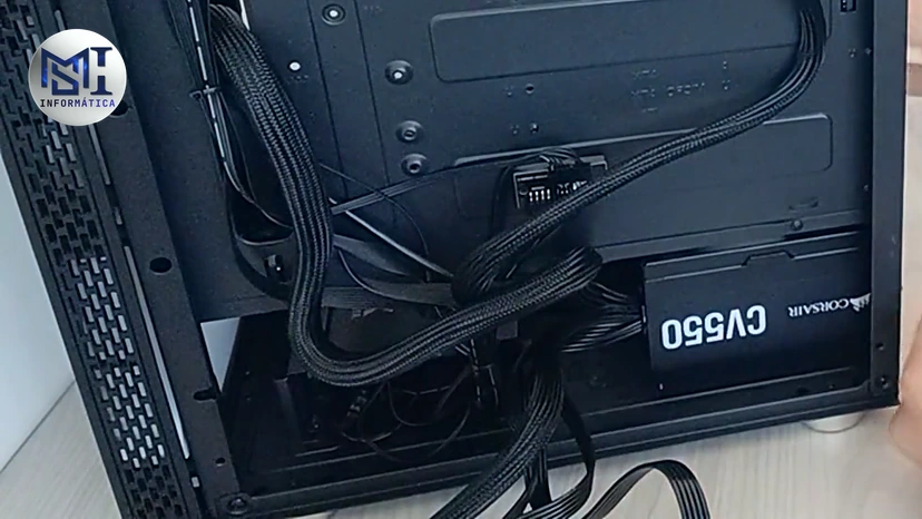 Fonte Corsair CV550 nova instalada embaixo do gabinete de um PC de cliente, vista por trás da placa-mãe, no vídeo do canal