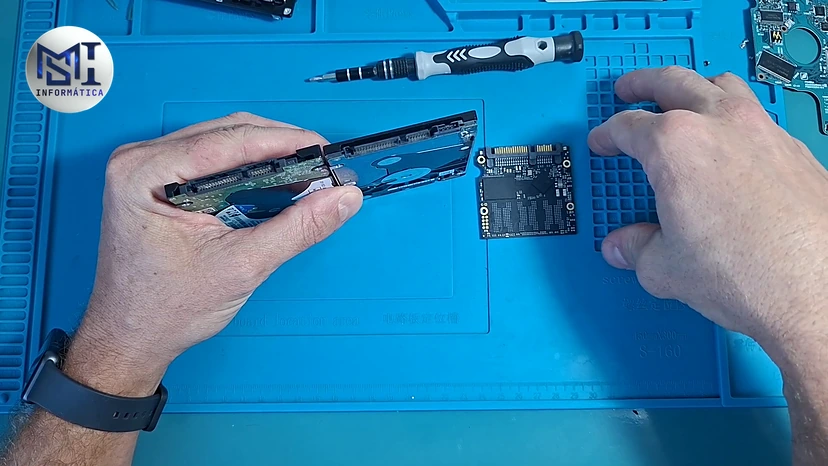 HD de notebook na mão do técnico ao lado da placa de um SSD SATA de 2,5 polegadas aberto, no vídeo do canal
