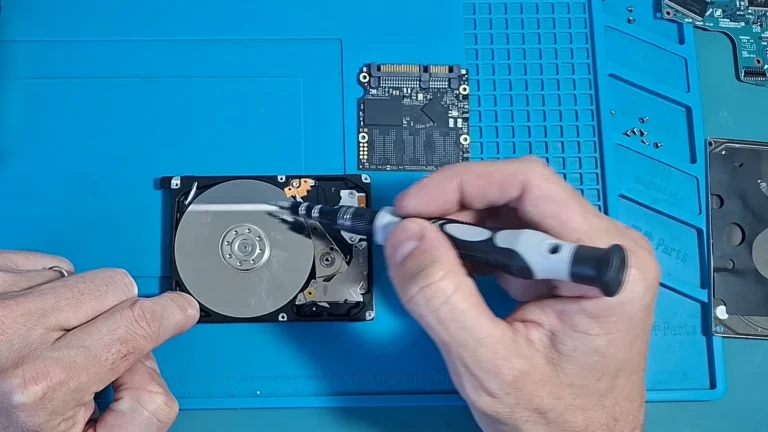 HD mecânico aberto com o prato à mostra e um SSD aberto ao lado, na mesa, no vídeo do canal sobre HD e SSD