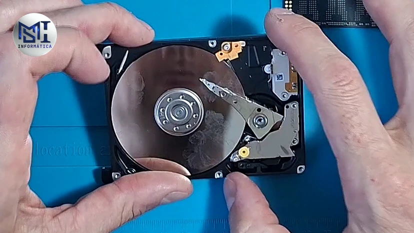 HD mecânico aberto nas mãos, com o prato e a cabeça de leitura à mostra, no vídeo do canal sobre SSD