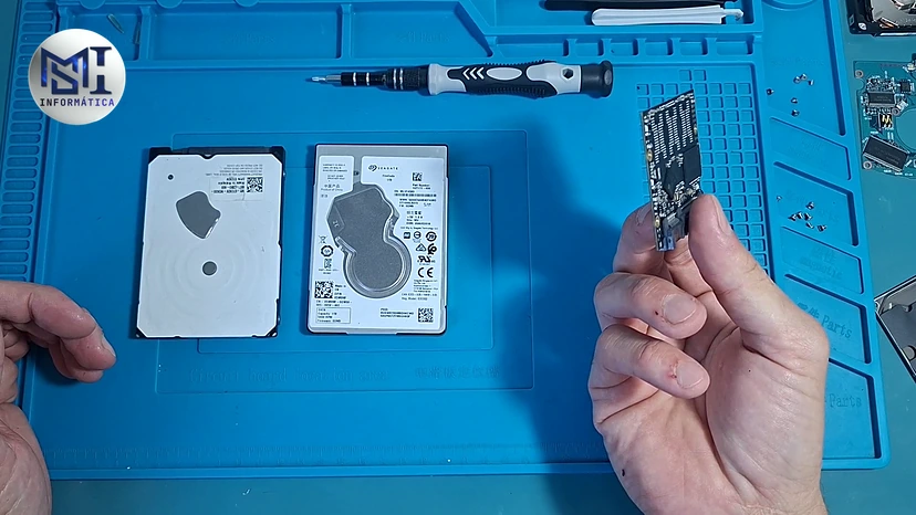Dois HDs de notebook sobre a manta e, na mão, a placa de dentro de um SSD SATA de 2,5 polegadas, no vídeo do canal