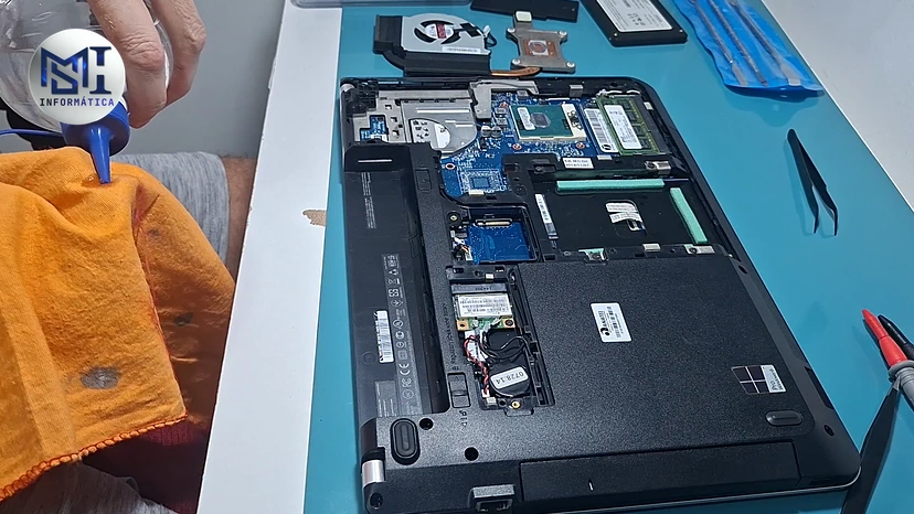 Limpeza interna de um notebook Lenovo aberto, com álcool isopropílico no pano, no vídeo do canal