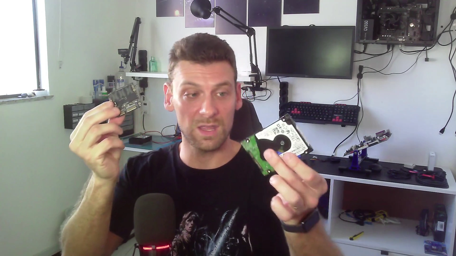 Marcello Di Silvestro segurando a placa de um SSD e um HD de notebook, no vídeo do canal