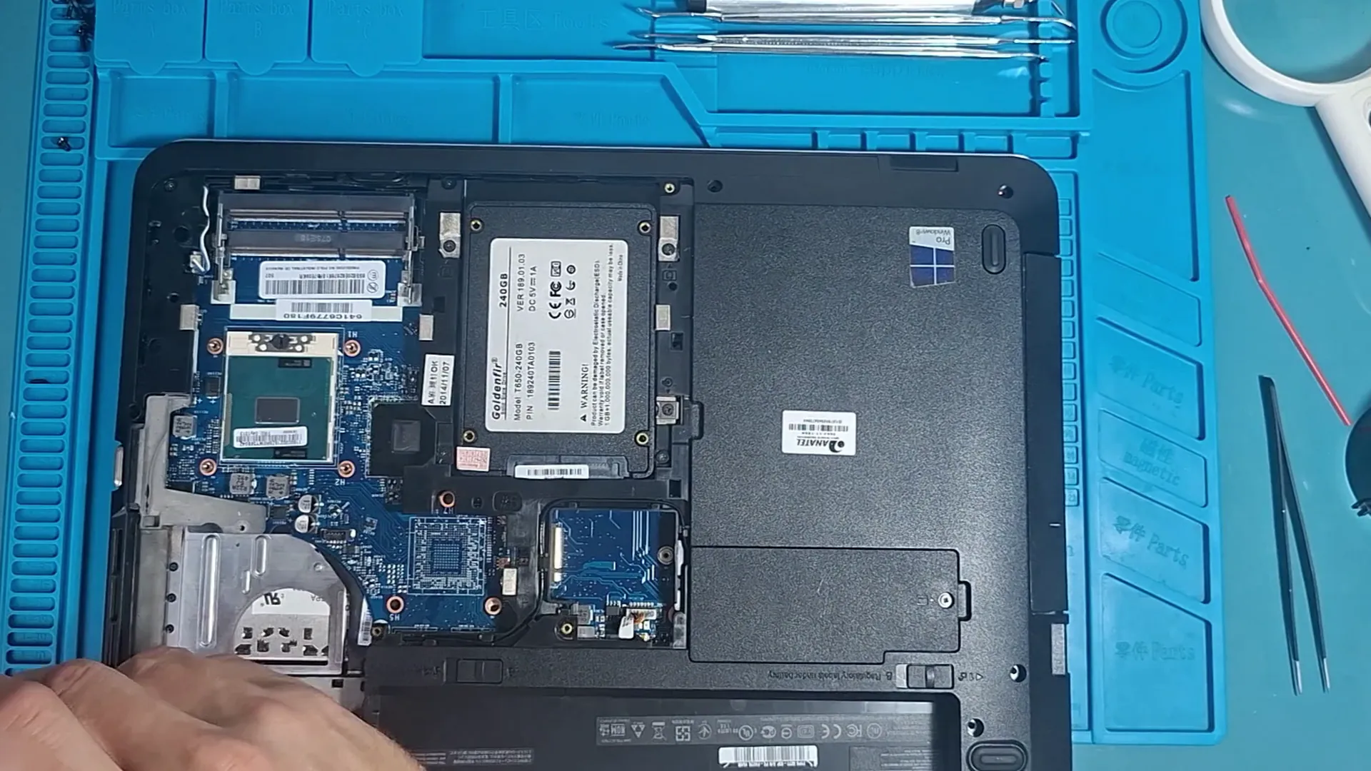 Notebook Lenovo aberto por baixo sobre a manta de manutenção, com a placa-mãe, a memória e o SSD à mostra