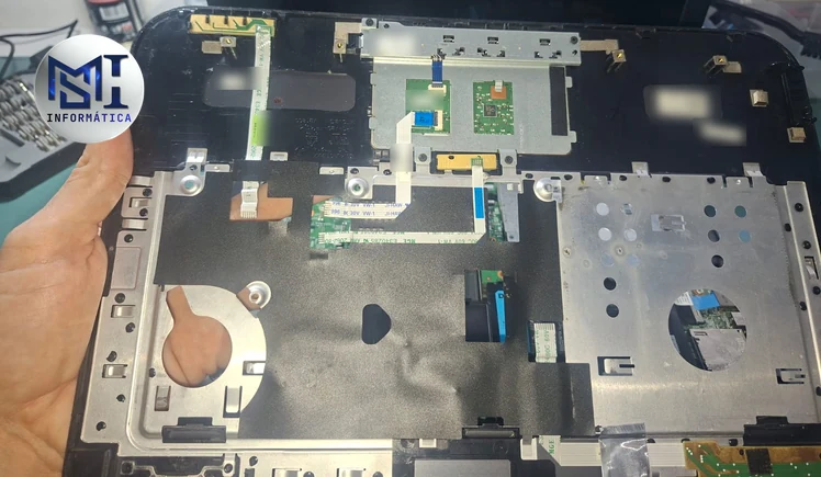 Notebook Dell Inspiron aberto sem o teclado, com os cabos flat que ligam o touchpad e as plaquinhas internas à placa-mãe