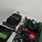 Peças de um PC gamer de cliente separadas na mesa: placa-mãe com o cooler, placa de vídeo e SSD, no diagnóstico