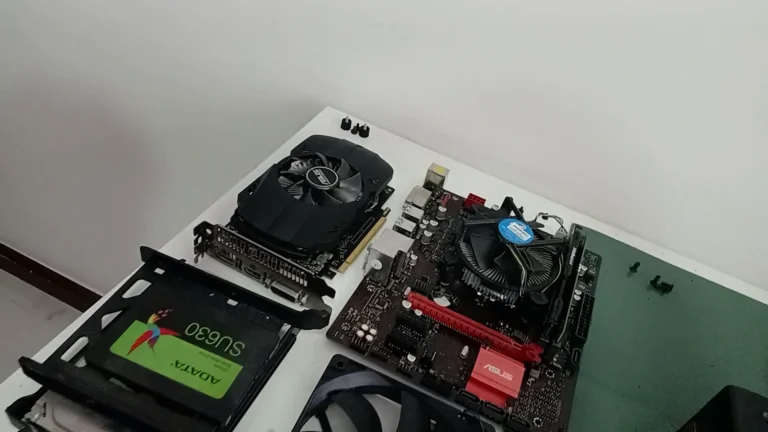 Peças de um PC gamer de cliente separadas na mesa: placa-mãe com o cooler, placa de vídeo e SSD, no diagnóstico