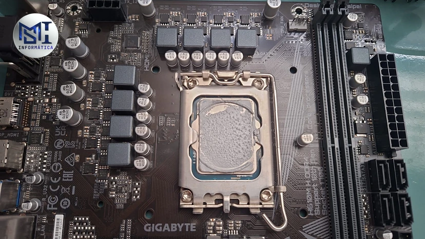 Processador Intel no soquete LGA 1700 de uma placa-mãe Gigabyte H610M com a pasta térmica espalhada na tampa