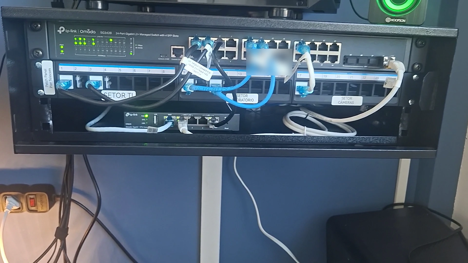 Rack de rede do escritório da MSI com switch gerenciável, patch panel identificado por setor e roteador