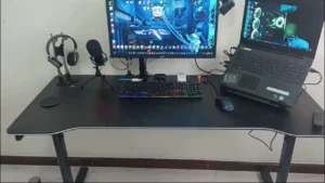 Setup do canal: mesa gamer preta com monitor LG, teclado mecânico com luz, mouse, headset no suporte, microfone e notebook