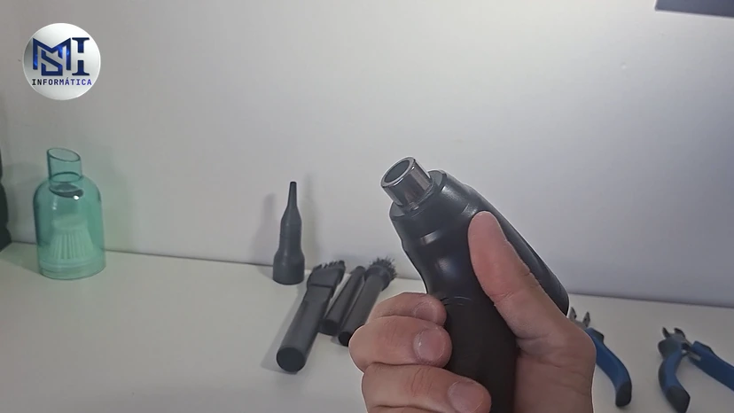 Soprador elétrico na mão do técnico, com os bicos e as escovinhas sobre a mesa, no vídeo do canal