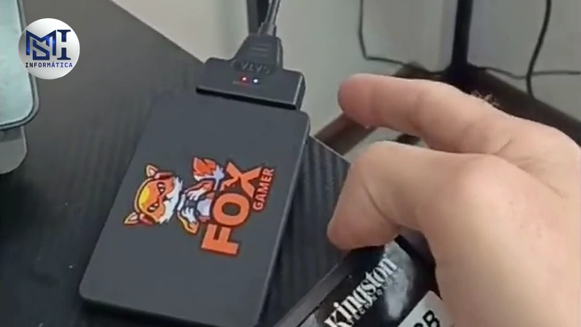 SSD num adaptador USB ligado por cabo e outro SSD na mão do técnico, no vídeo do canal