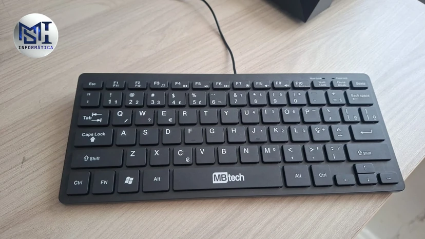 Teclado fino MBtech com fio, de teclas baixas, sobre uma mesa clara